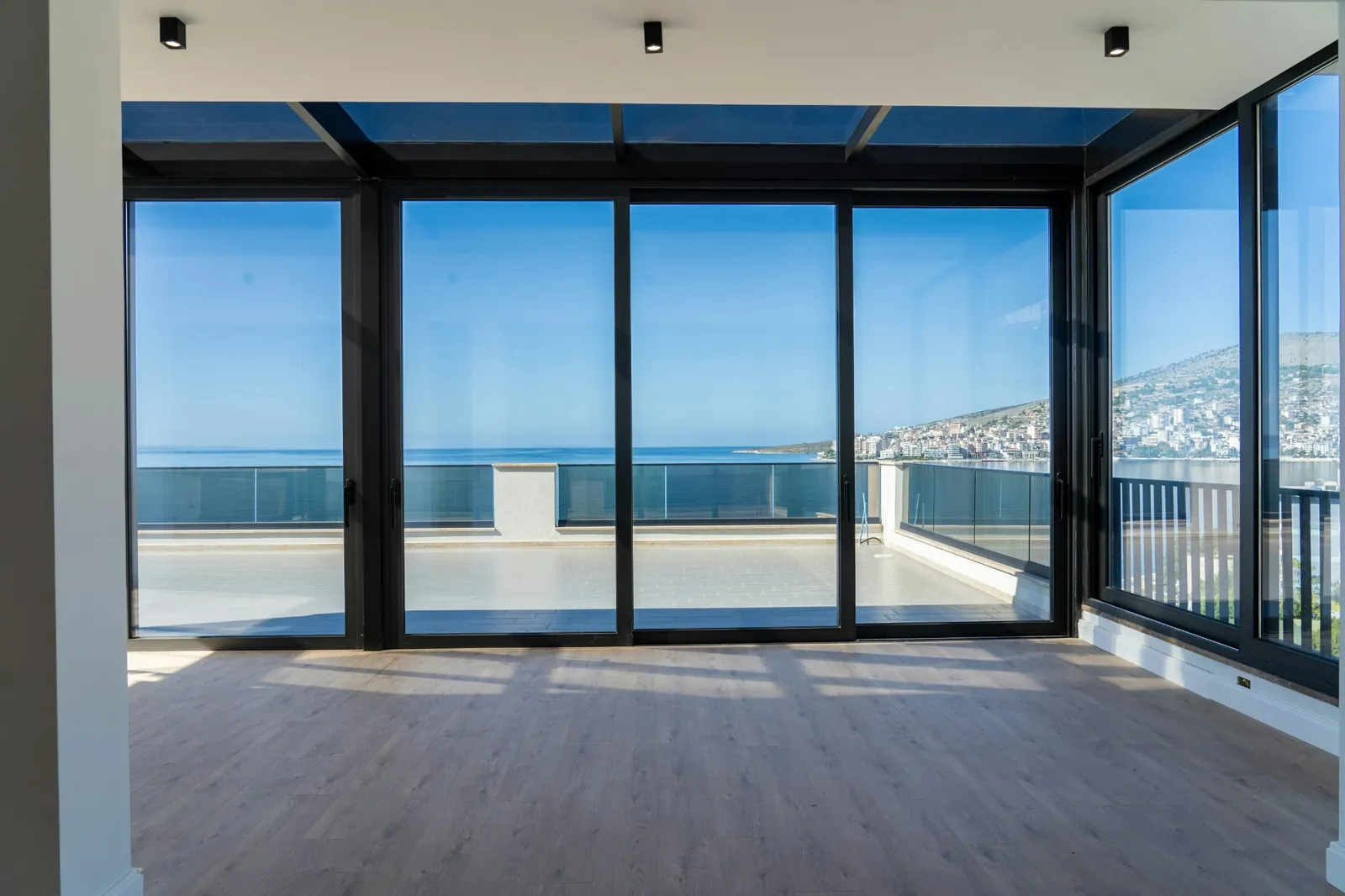 A bright apartment with floor-to-ceiling windows opening onto a terrace with a sea view